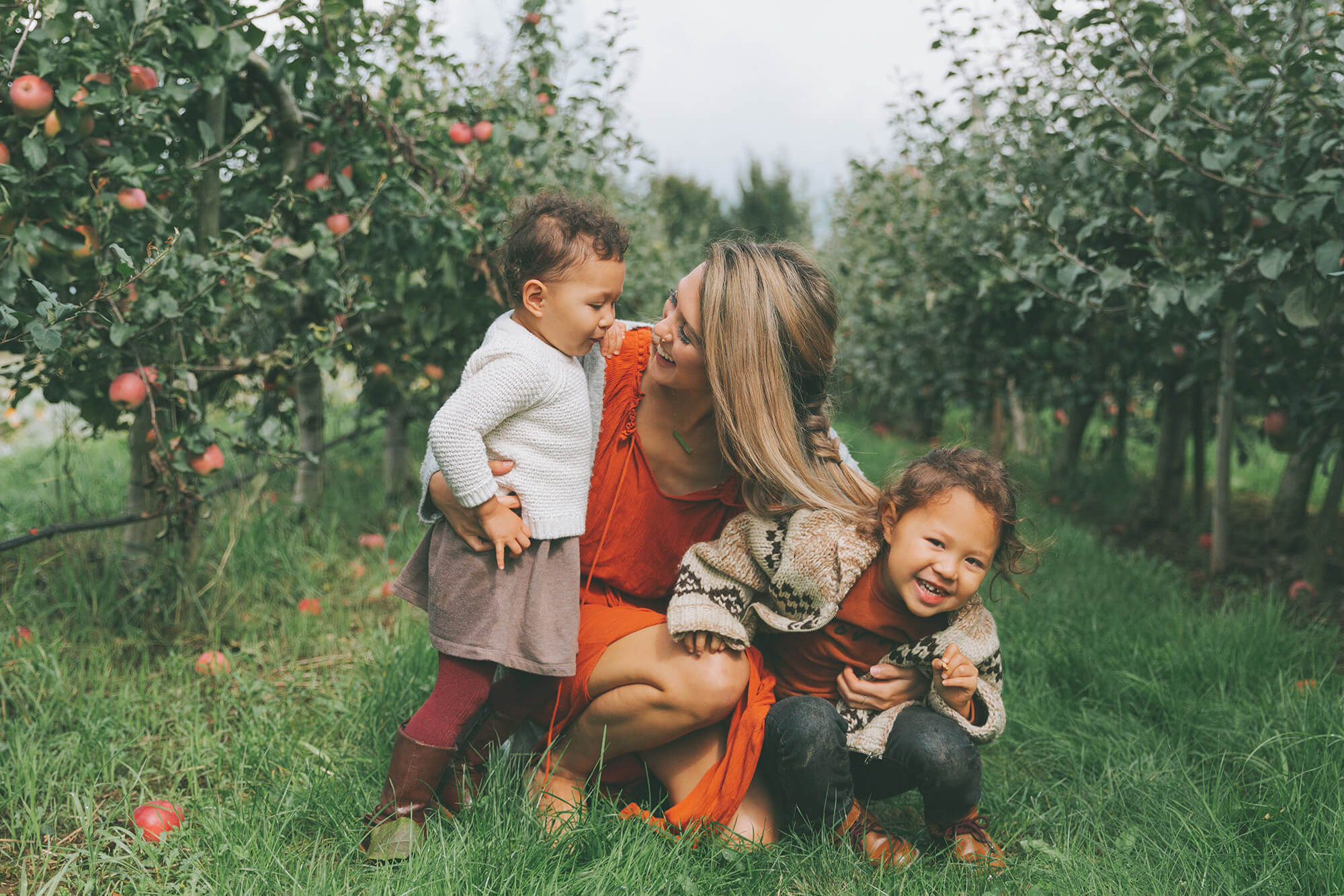 A mother and children in an apple orchard in the fall